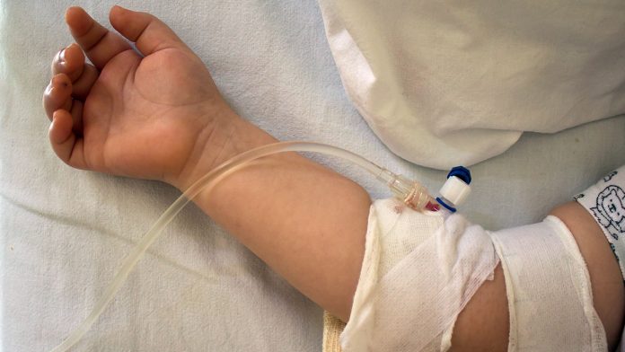 Child in hospital bed with saline intravenous.Little patient