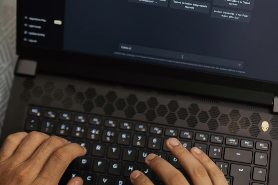 Pessoa usando um laptop com interface de chatbot em tela escura